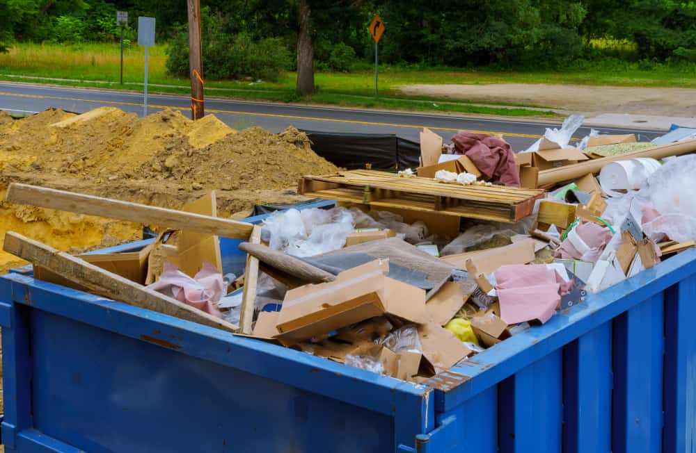 Blue,Construction,Debris,Container,Filled,With,Rock,And,Concrete,Rubble.